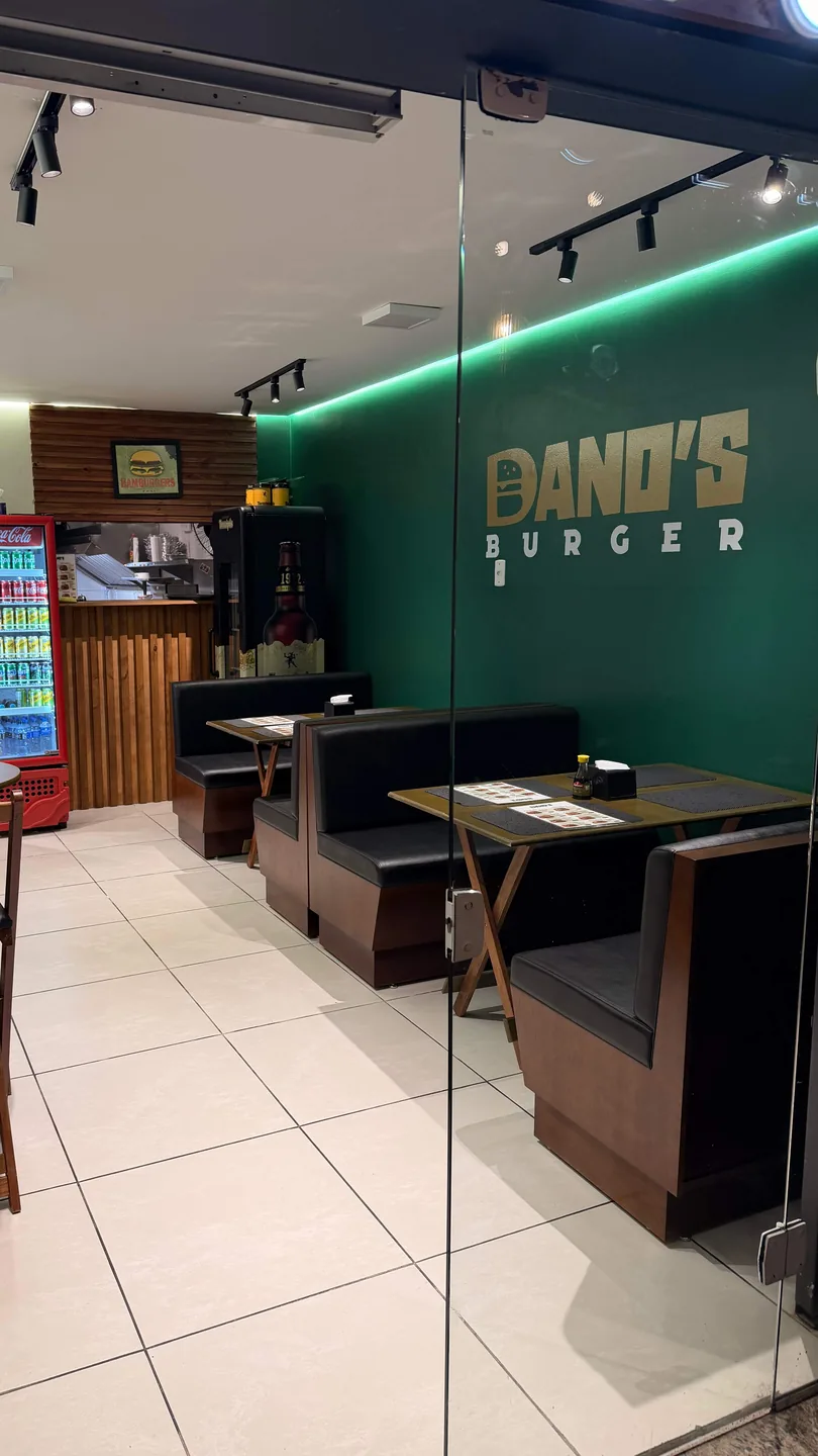 Salón de Dano's Burger con pared verde, Logo y mesas