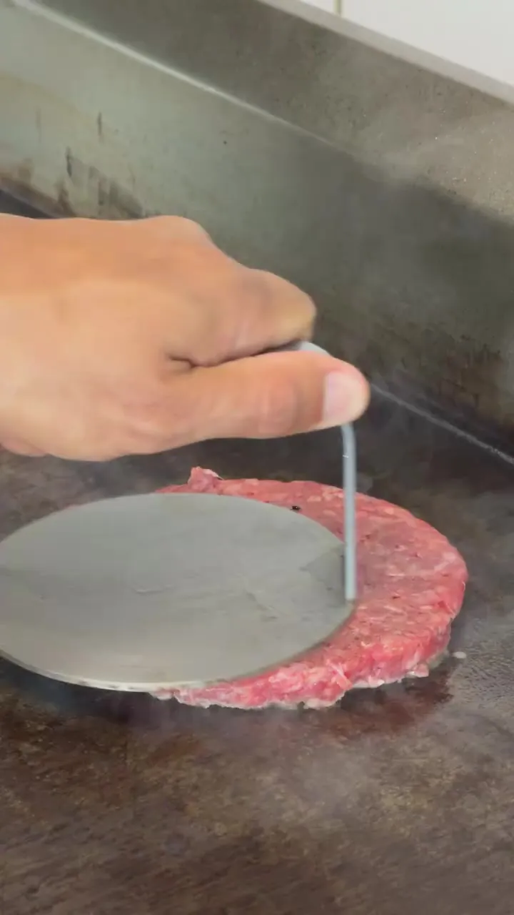 La carne aplastándose en la plancha caliente